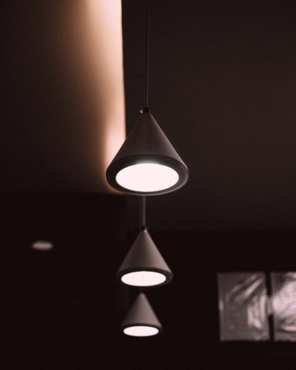 Elegant cone-shaped pendant lights creating a modern atmosphere in a dark interior space.